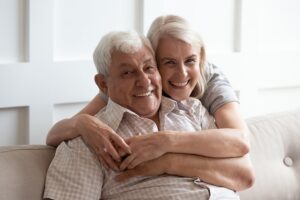 A couple smiling, embracing and sitting on the couch